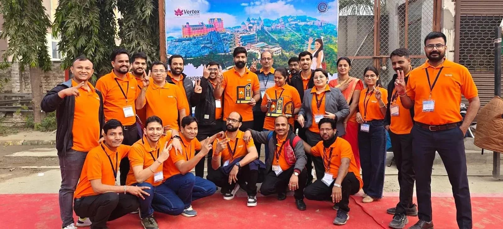 Secure Meters colleagues in orange shirts posing together outdoors at an event.
